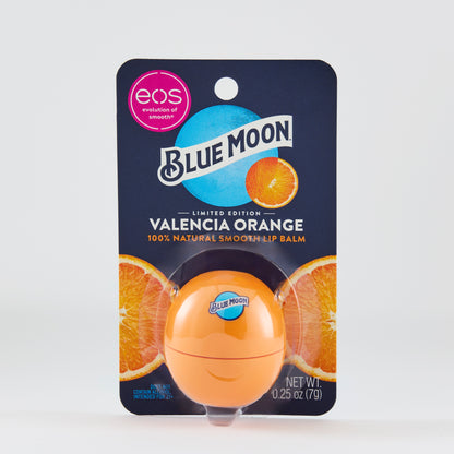 Orange eos-style lip balm package with a Blue Moon–branded orange container inside. The card reads: “BLUE MOON,” “VALENCIA ORANGE,” and “100% NATURAL SMOOTH LIP BALM,” with sliced orange images behind the product.