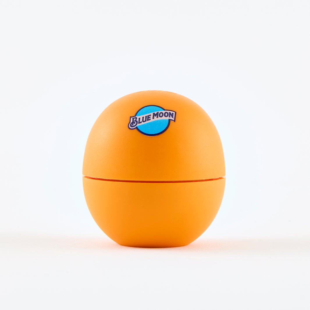 Orange eos-style lip balm container with the Blue Moon logo printed on the front.
