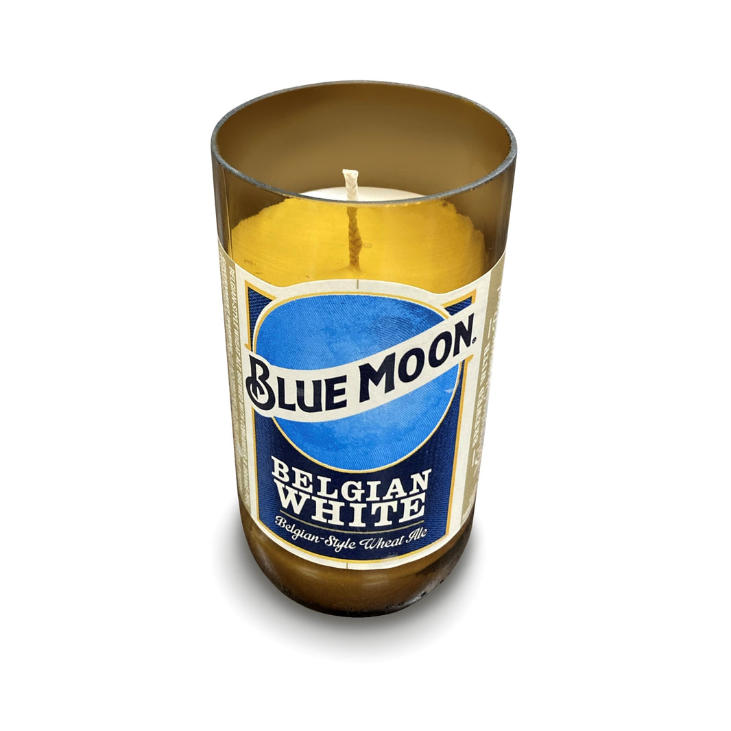 Amber glass candle holder made from a cut Blue Moon Belgian White bottle with the label facing forward and a white candle inside.