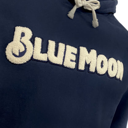 Cream textured “BLUE MOON” lettering on a navy hoodie shown in close-up.
