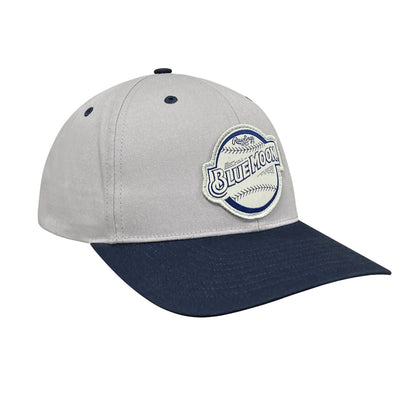 Light gray baseball cap with a navy brim and a stitched patch on the front reading “BLUE MOON” with baseball-style stitching details.