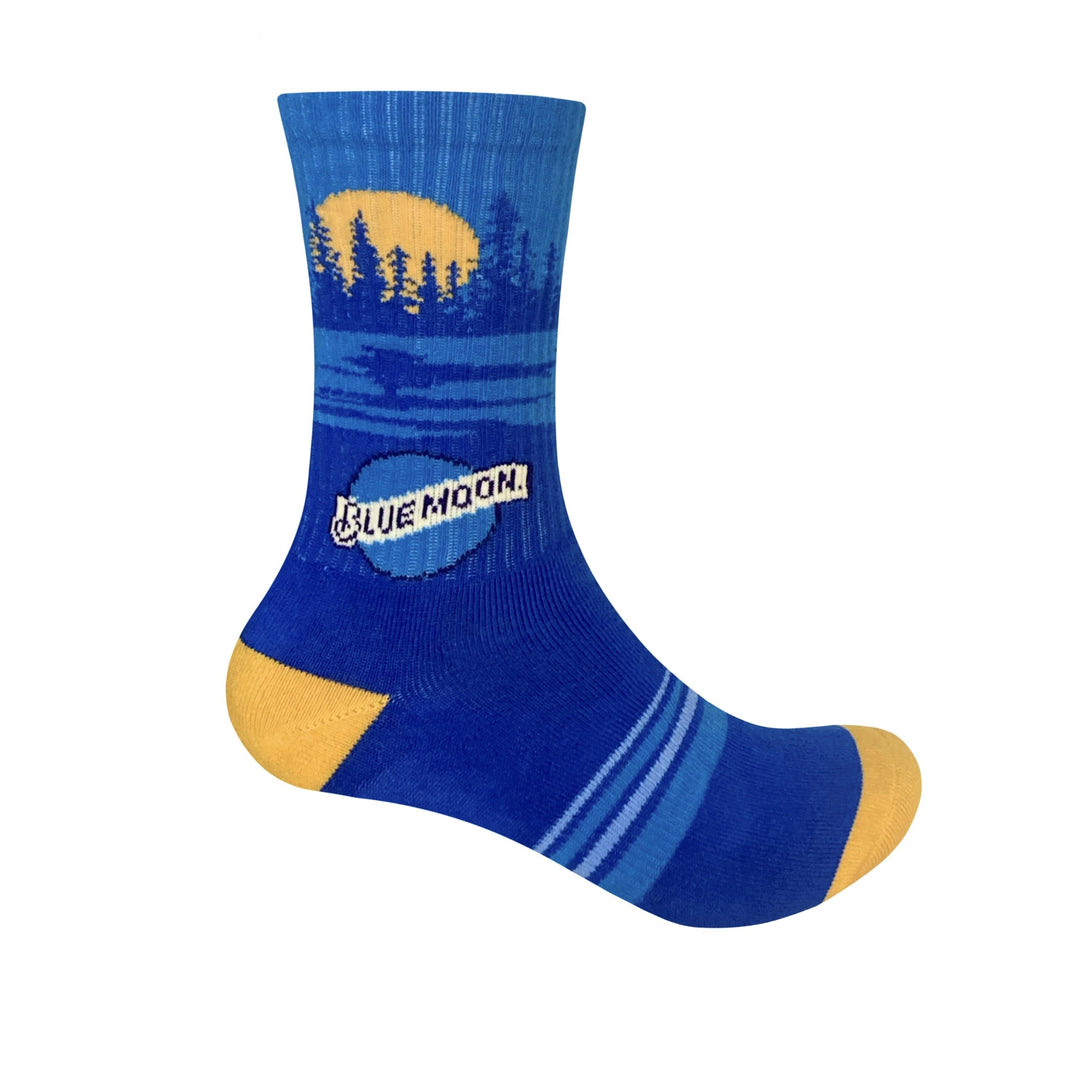 Blue sock with a landscape design of trees and a yellow moon near the top, blue stripes on the foot, yellow heel and toe, and a Blue Moon logo on the side.
